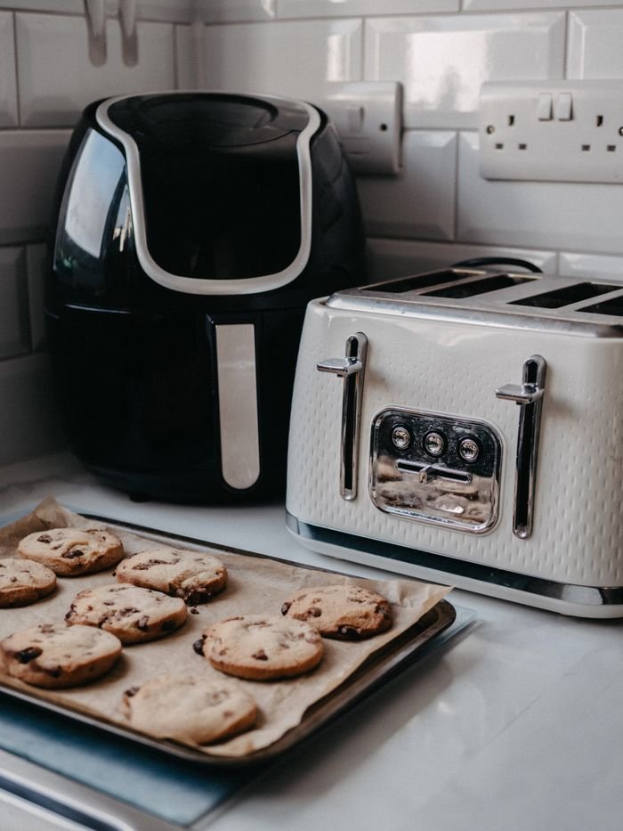Services Freshly baked cookies on tray beside air fryer and toaster.