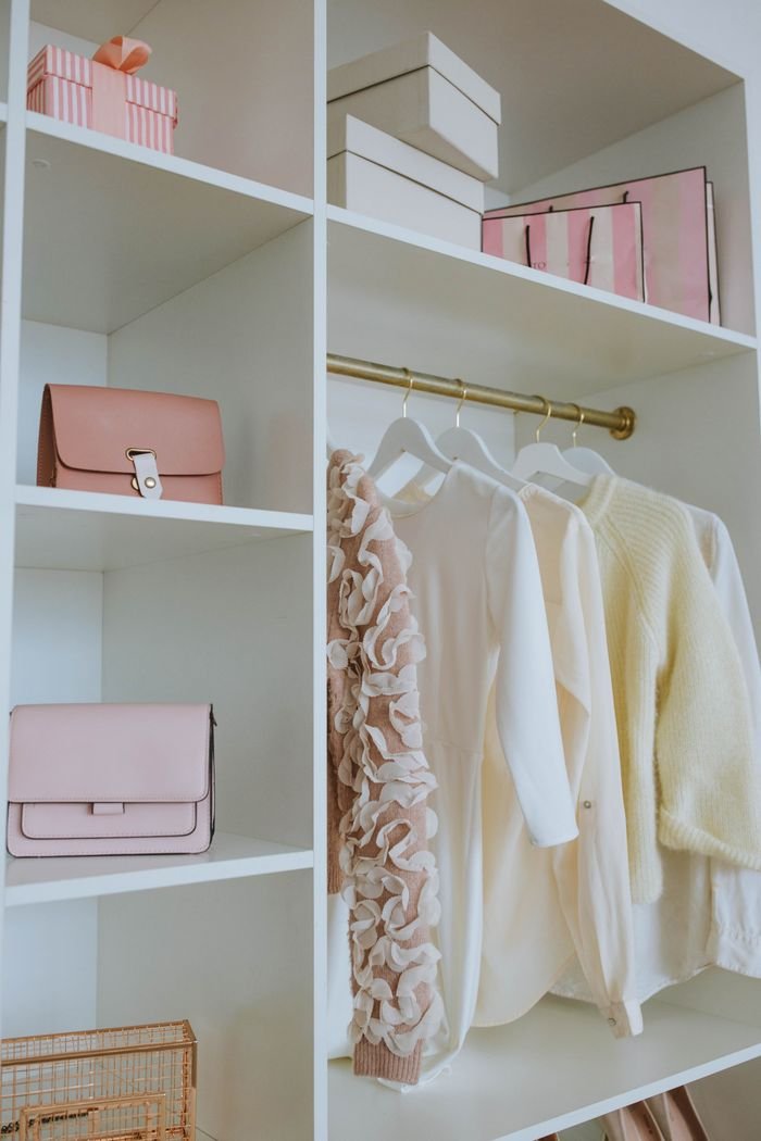 About Stylish feminine wardrobe with clothes, bags, and gifts neatly organized on shelves.